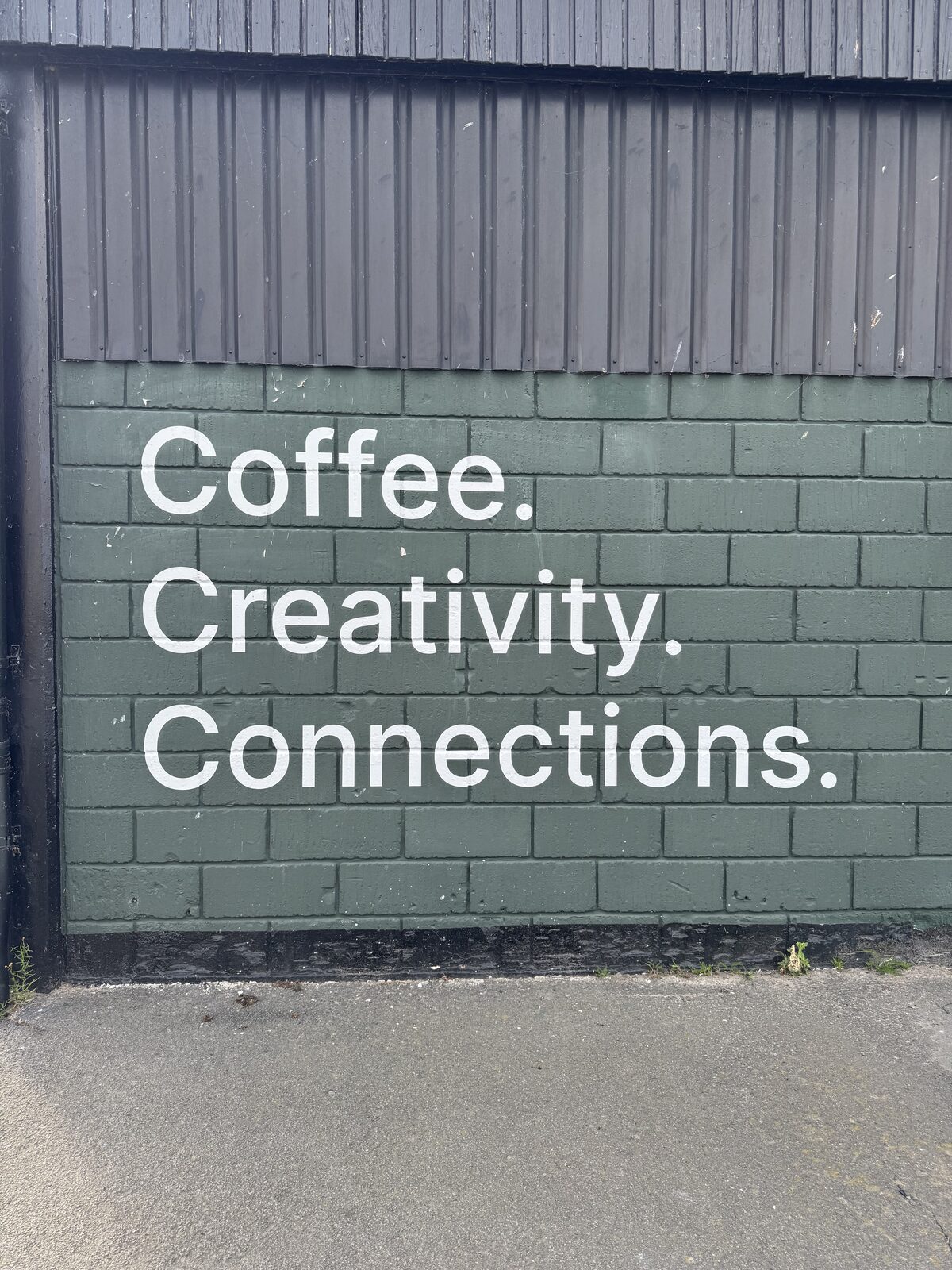 Schriftzug Coffee, Creativity, Connections auf einer dunklen Fassade